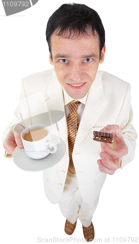 Image of Funny young man drinking coffee with sweets