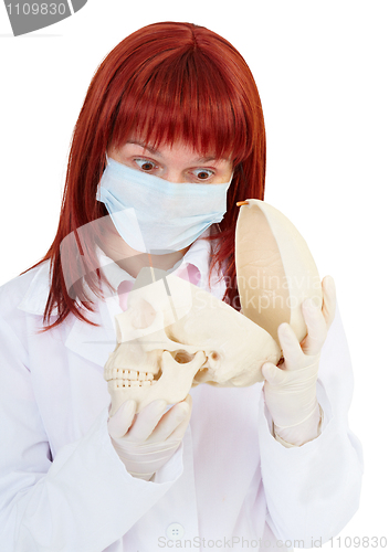 Image of Young woman in amazement looking at skull