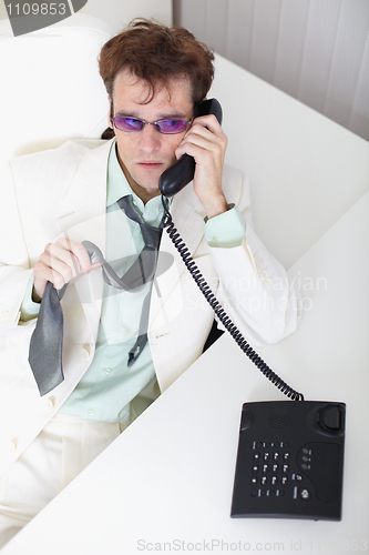 Image of Uneasy young businessman speaks on phone