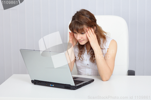 Image of Young tired woman working with laptop at table