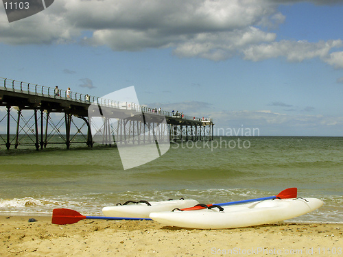 Image of Two canoes on the shore with a pier in the background