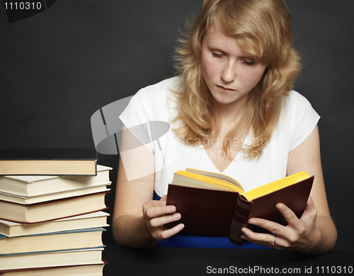 Image of Young woman reads book against dark background