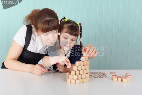 Image of Mother and daughter playing with toys at table