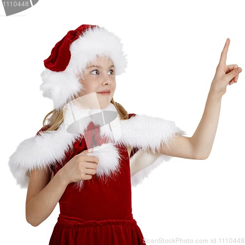 Image of Surprised smiling girl in Christmas clothes points a finger