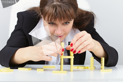 Image of Woman are concentrated in building a tower on table with domino