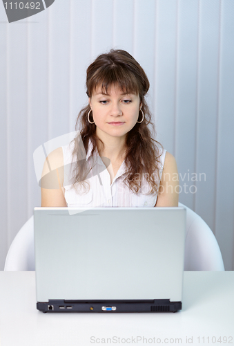 Image of Young woman working with laptop computer at table