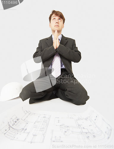 Image of Builder prays to god sitting near drawing