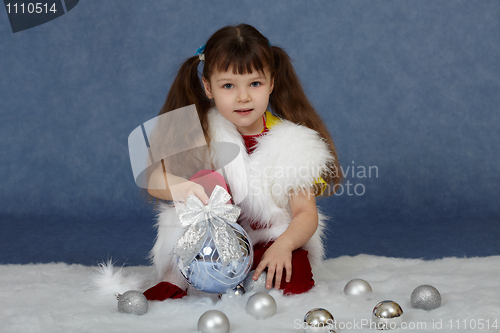 Image of Child sits on blue with Christmas tree ball