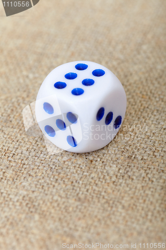 Image of One dice on brown canvas