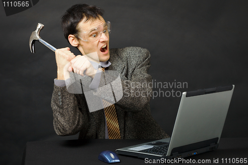Image of Furious young man breaks hammer computer