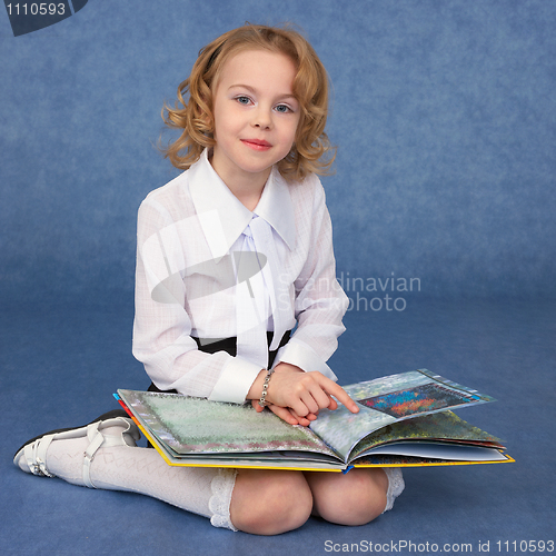 Image of Schoolgirl reading book sitting on floor