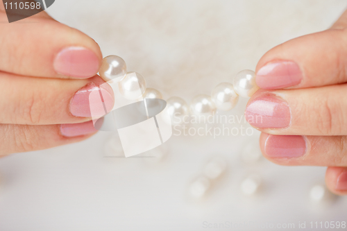 Image of Female fingers hold thread with pearls