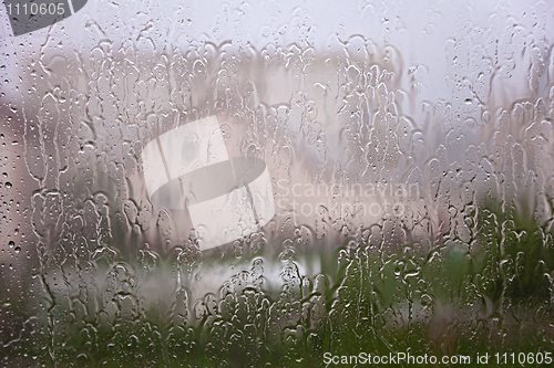 Image of View through window with streams and drops of rain water