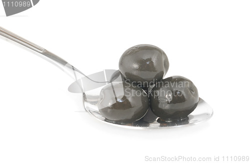 Image of Whole black olives marinated in stainless spoon isolated on white