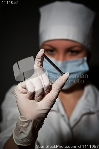 Image of young pretty surgeon holding nail for osteosynthesis