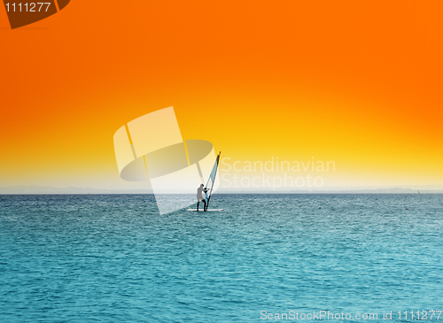 Image of surfer on blue sea under orange sky