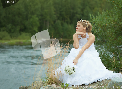 Image of Sad bride sits on river bank