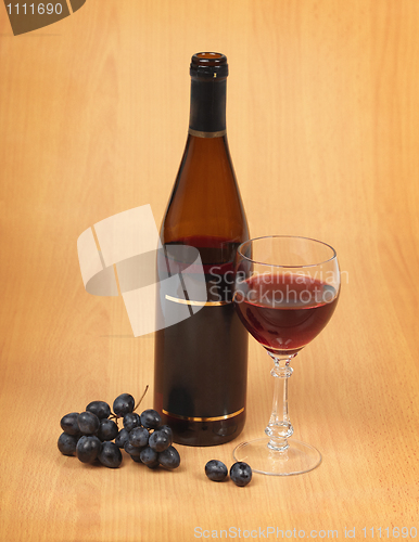 Image of Bottle, glass and grapes on wooden background