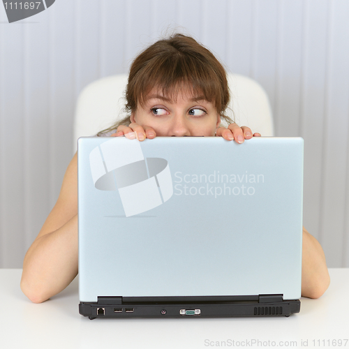 Image of Young woman hiding behind a laptop