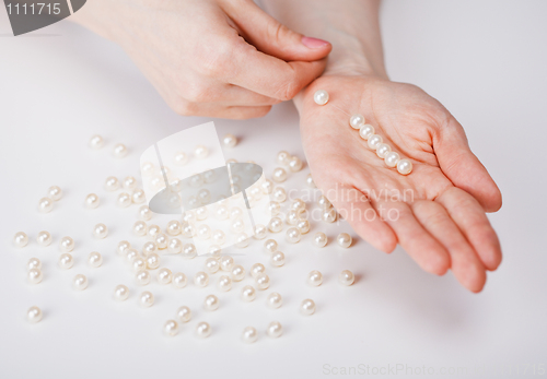 Image of Female hands collecting beads from pearls