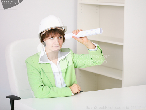 Image of The woman - builder in helmet with a drawing in hands