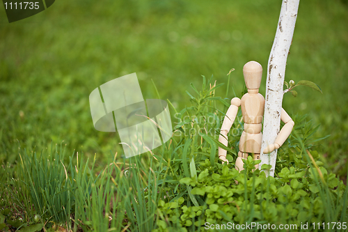 Image of Toy man embraces young tree