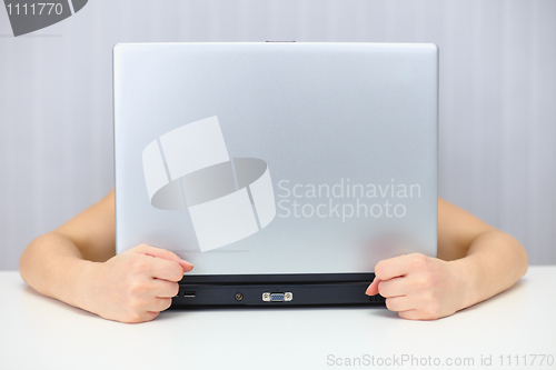 Image of Emotional woman hiding behind a laptop