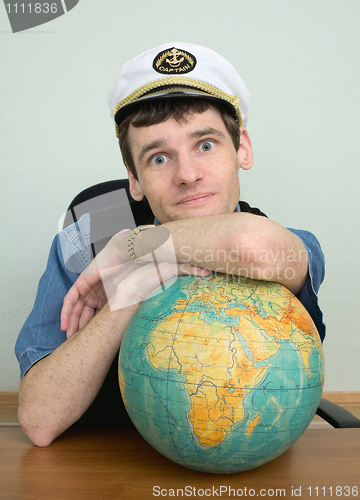 Image of Young man in a captain's cap with globe