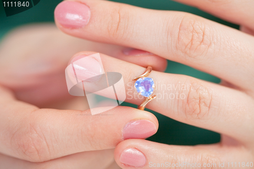 Image of Golden ring with blue jewel try on a finger