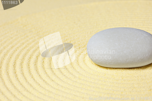 Image of Round stone lying on sand with circular pattern