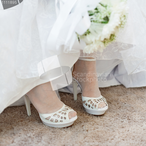 Image of Shoes of bride under wedding dress