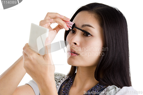 Image of young woman putting on black mascara 