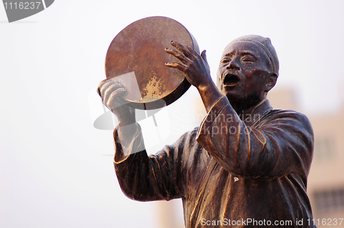 Image of Statue of a man singing with drum