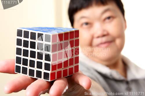 Image of senior chinese woman show a complete  rubik cube