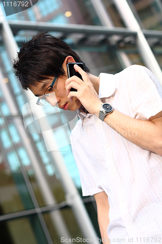 Image of young businessman in a suit holding mobile phone in front of mod