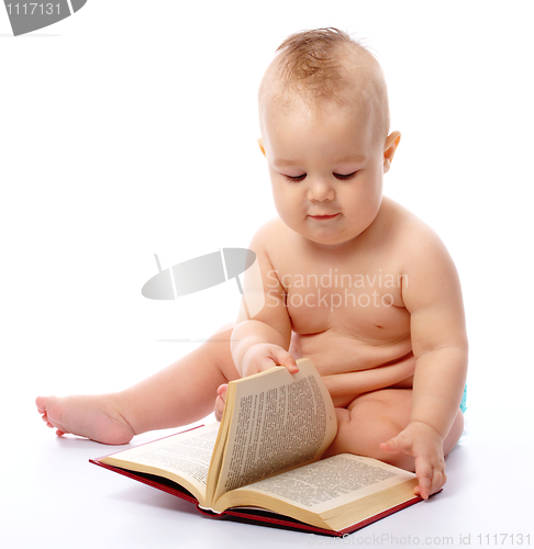 Image of Little child play with book and magnifier