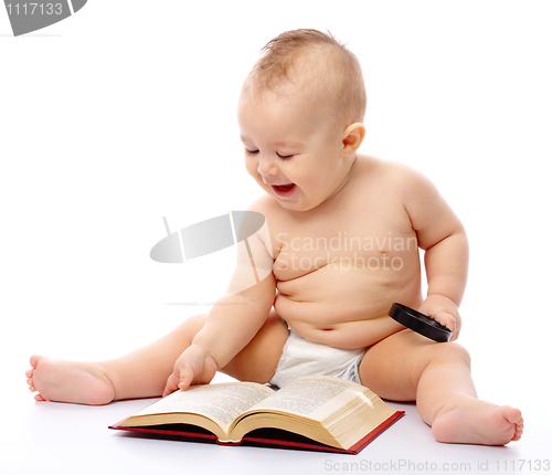 Image of Little child play with book and magnifier