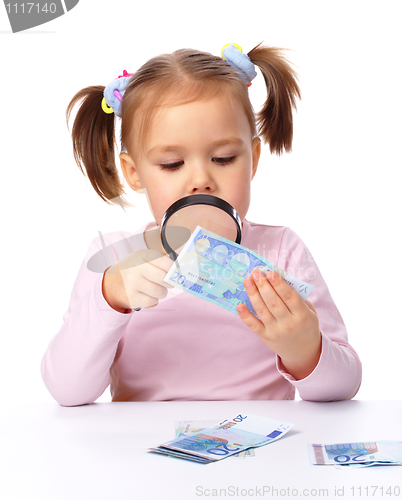 Image of Girl is looking at euro banknote using magnifier