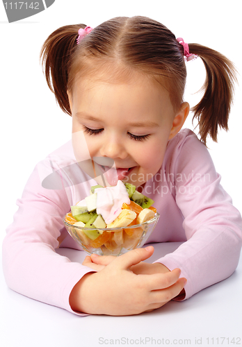 Image of Little girl licks fruit salad