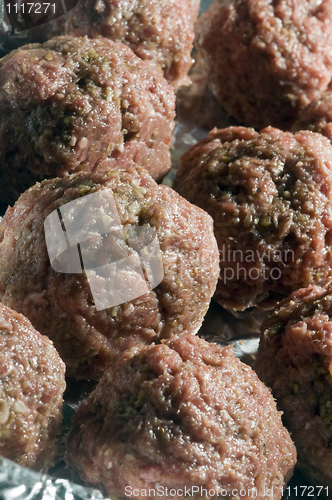 Image of raw meatball in foil wrapped cooking 