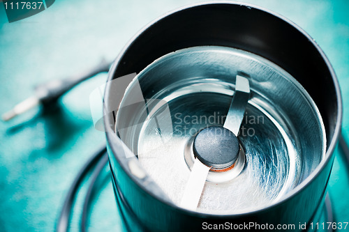 Image of Empty electrical coffee-mill machine on the green tabletop (without top cover)