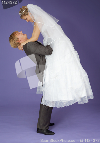 Image of Strong groom holds admired bride on hands