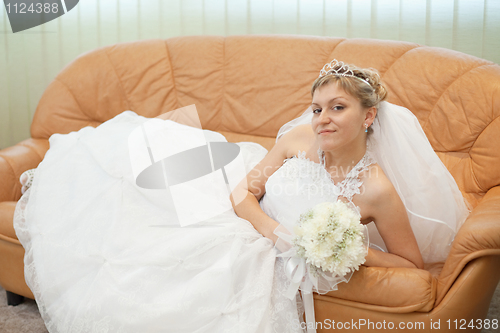 Image of Bride comfortably lies on big leather sofa