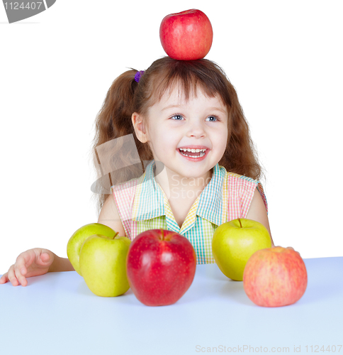 Image of Happy girl playing with apples sitting at table