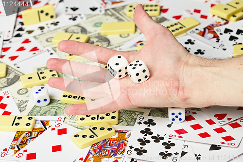 Image of Dice on palm on the background cards and money