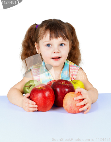 Image of Little girl playing with apples sitting at table