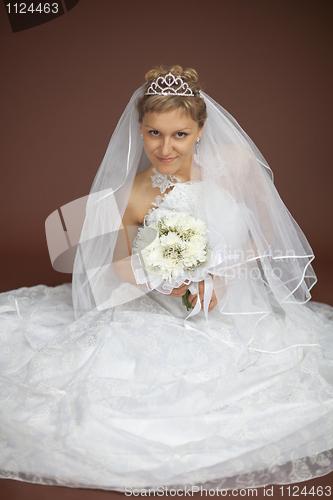 Image of Bride in white dress sits on brown background