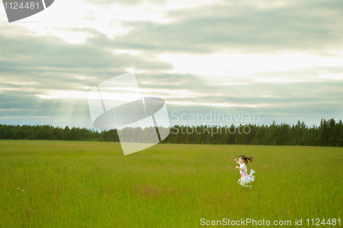 Image of Little girl in dress runs on meadow