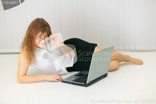 Image of Beautiful young woman with laptop lying on floor