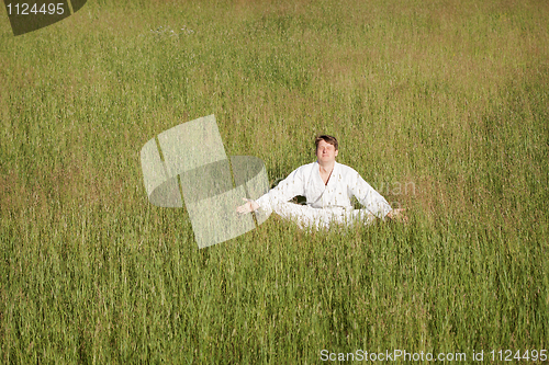 Image of Man in kimono meditates sitting in grass